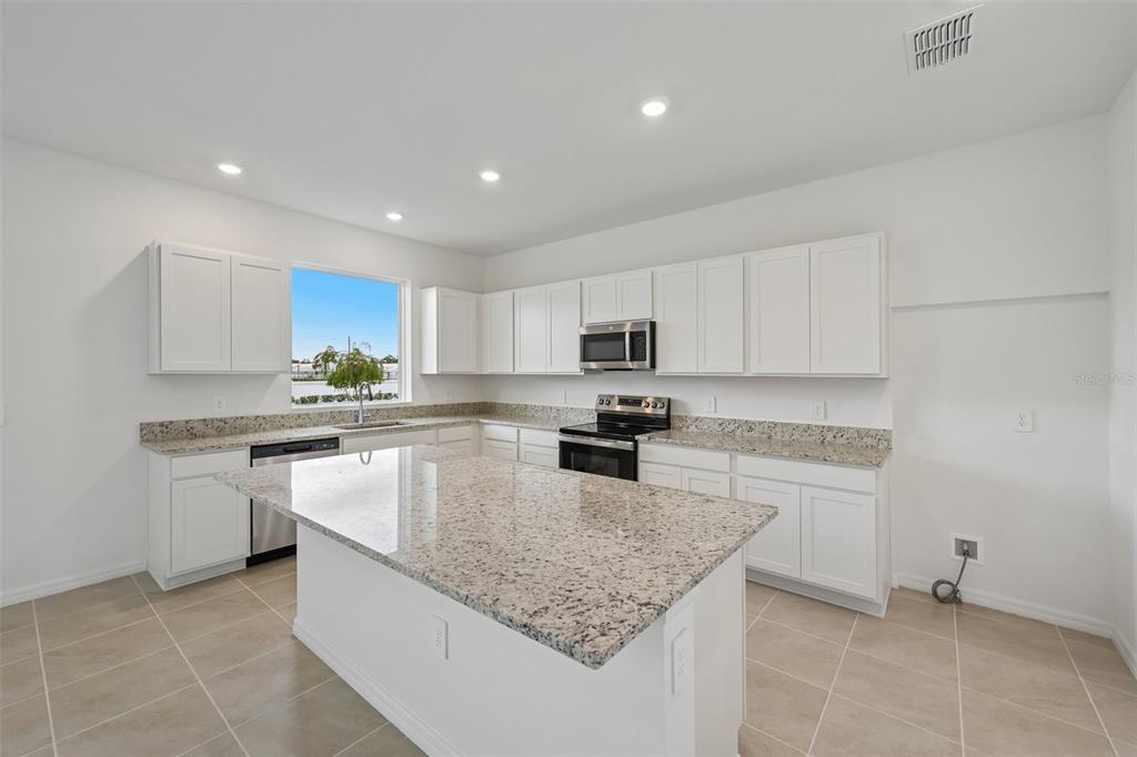 A kitchen with white cabinets, granite countertops, a central island, and stainless steel appliances — 4508 OUTHAUL RUN, PALMETTO, FL