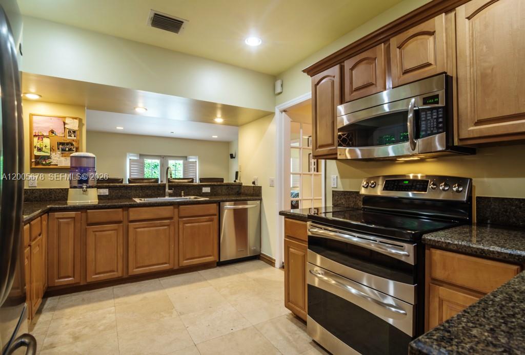 A white single-story house with a tile roof, arched entryway, and a paved driveway — 1237 Aduana Ave, Coral Gables FL 33146, CORAL GABLES, FL