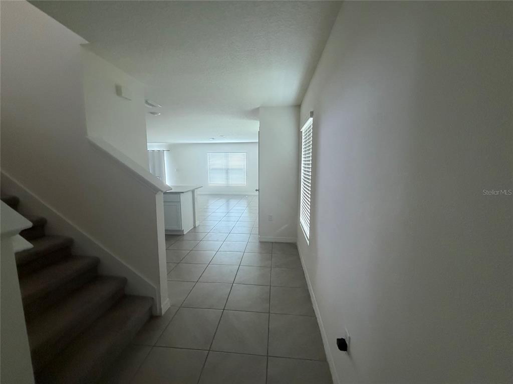 A tiled hallway leads past a carpeted staircase toward an open kitchen and living area — 12153 WHITE CYPRESS PLACE, RIVERVIEW, FL