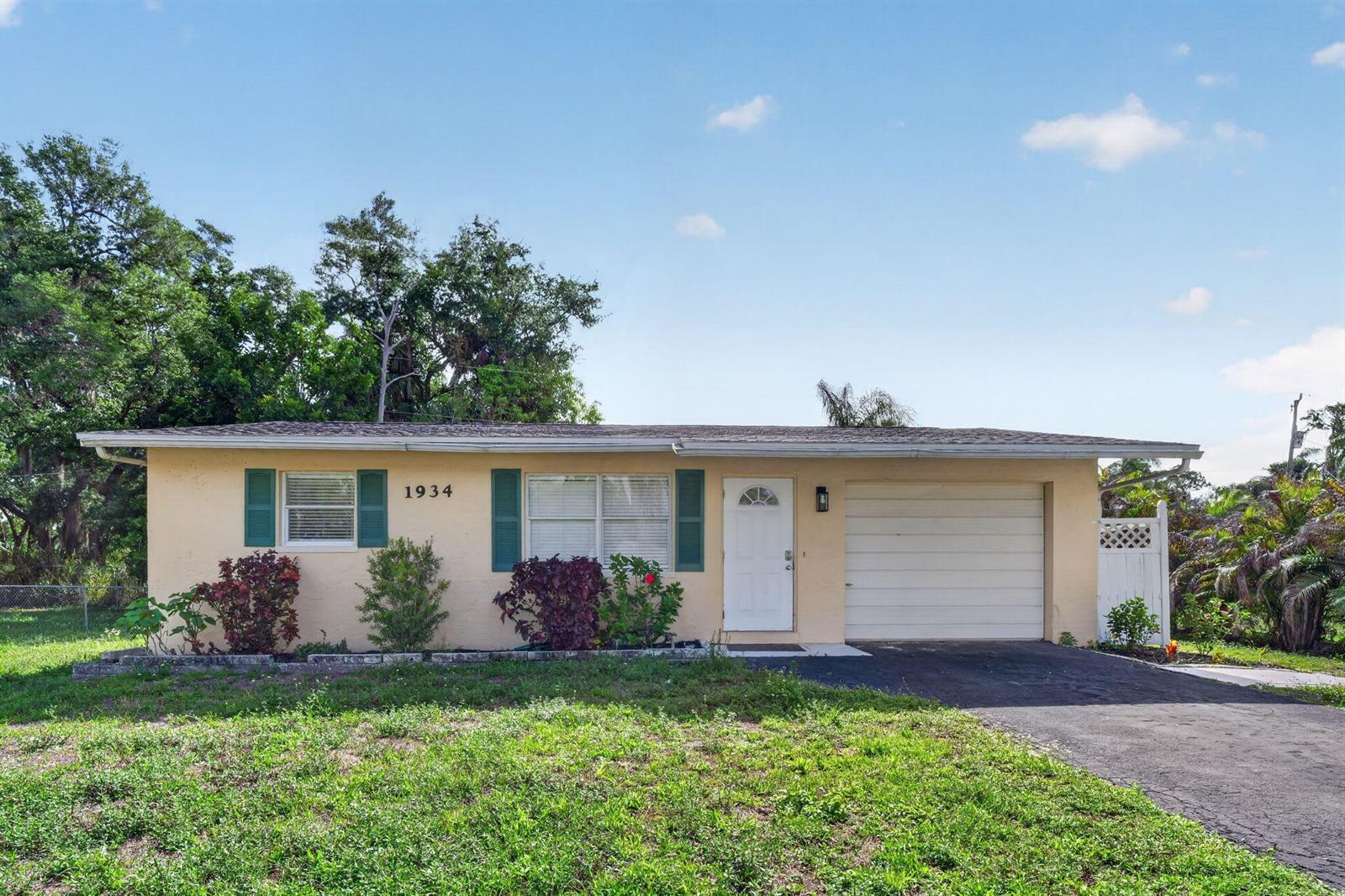 A single-story house with a yellow stucco exterior, green shutters, and an attached garage — 1934 Flamingo Drive, FL 33917, FL