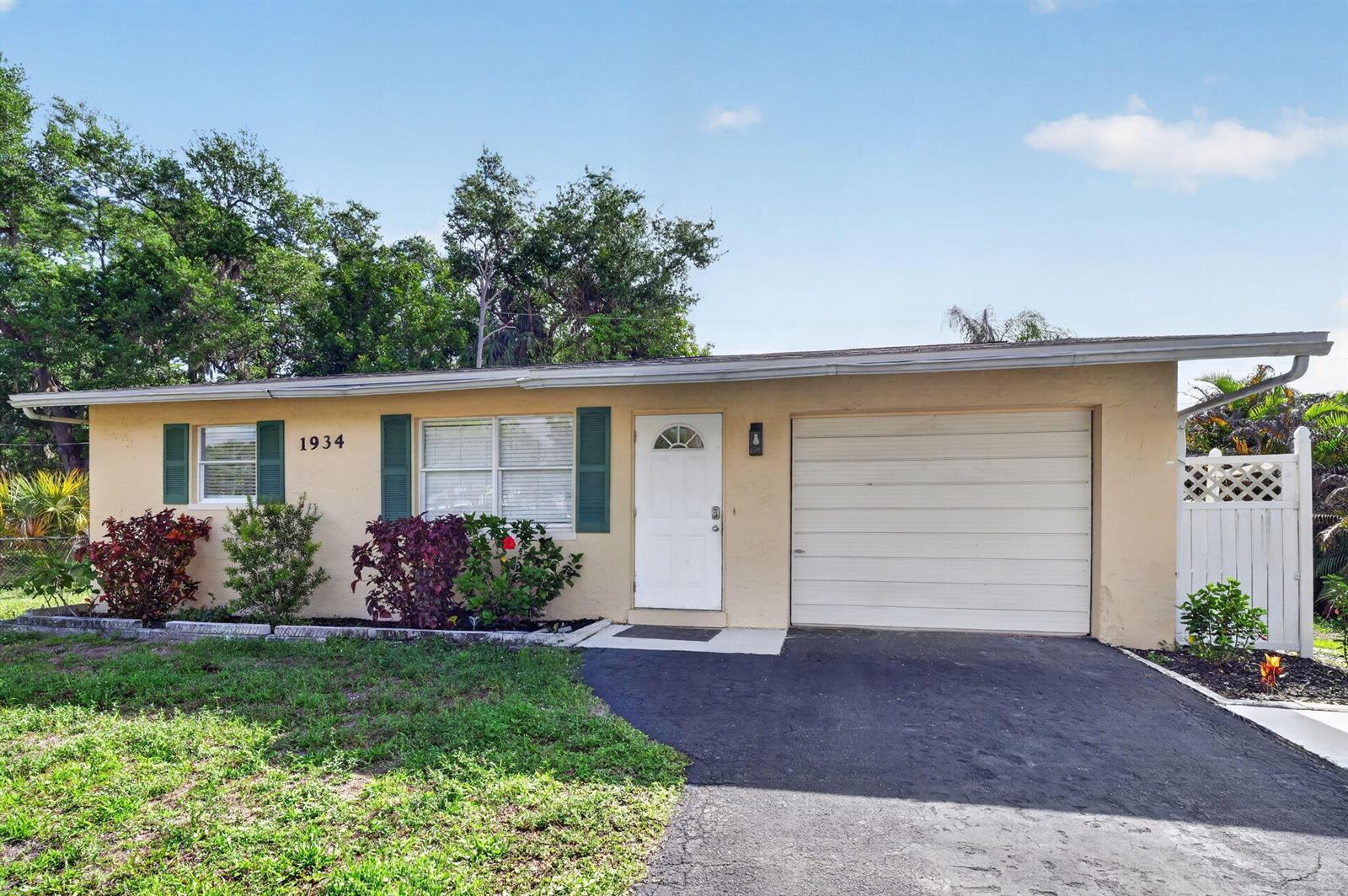 A single-story house with a tan exterior, green shutters, a white front door, and a garage — 1934 Flamingo Drive, FL 33917, FL