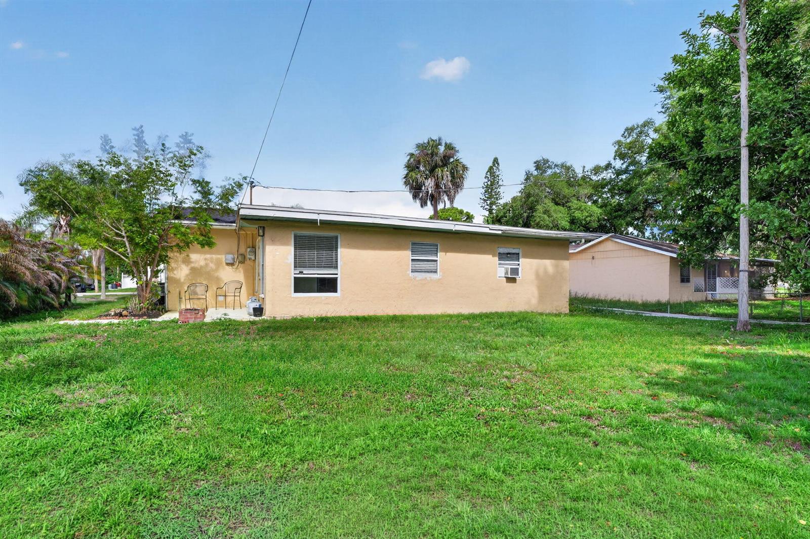 The exterior of a tan, single-story house features a grassy backyard and several windows — 1934 Flamingo Drive, FL 33917, FL