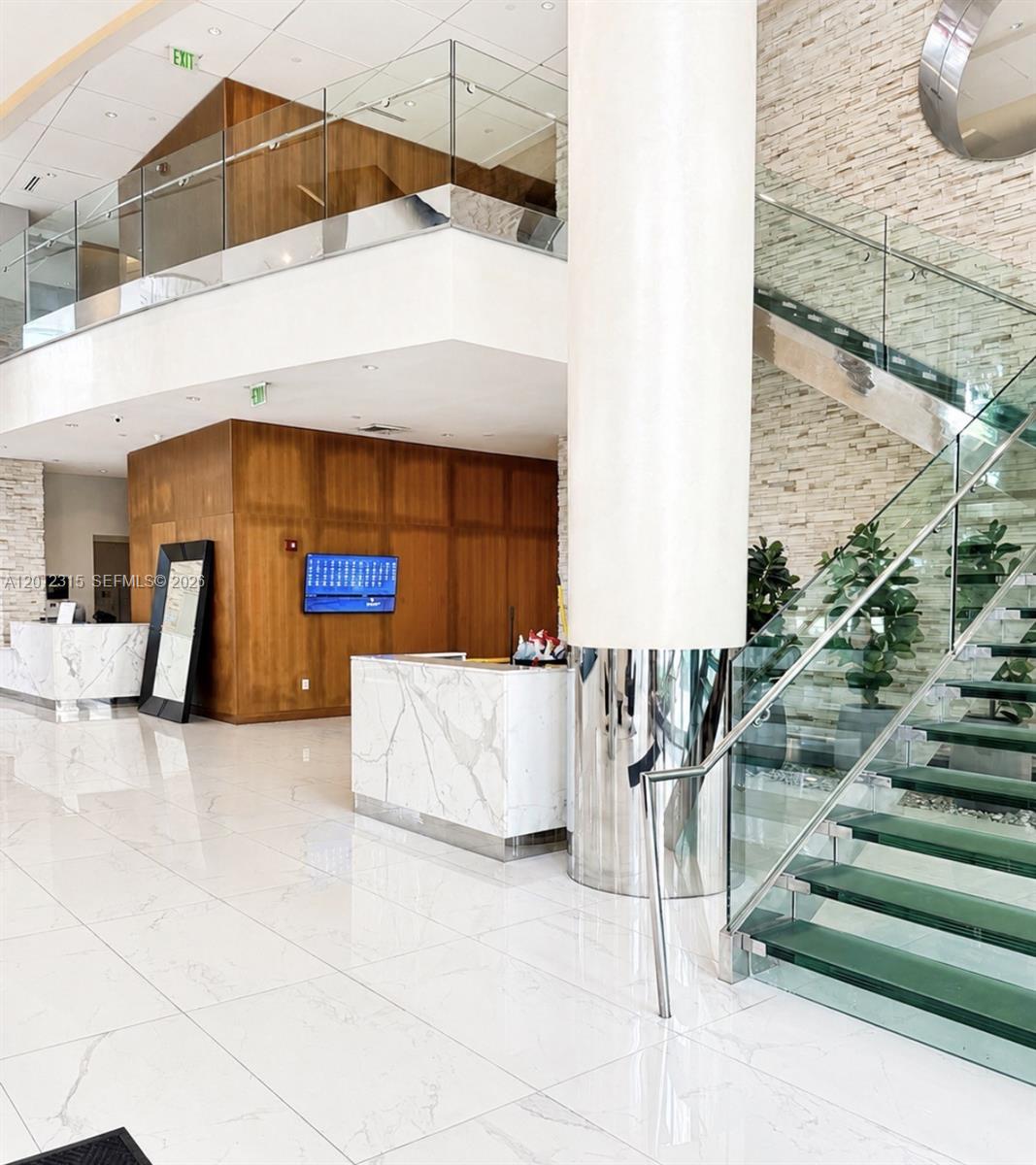 A modern lobby features marble reception desks, a glass staircase, and wood-paneled walls — 41 SE 5th St # 2011, Miami FL 33131, MIAMI, FL