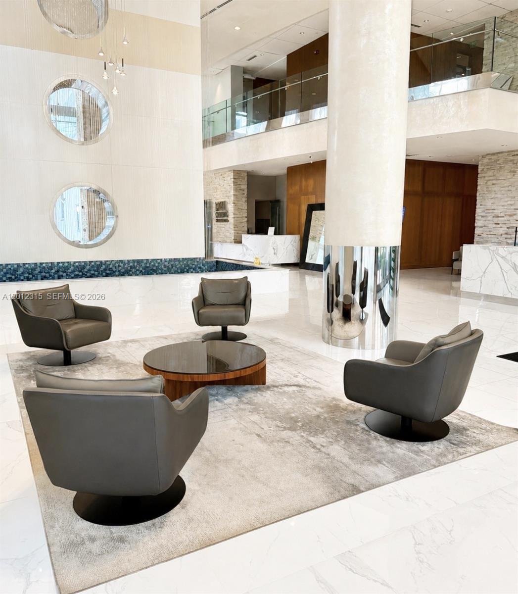 A modern lobby features a seating area with four gray swivel chairs and a round table — 41 SE 5th St # 2011, Miami FL 33131, MIAMI, FL