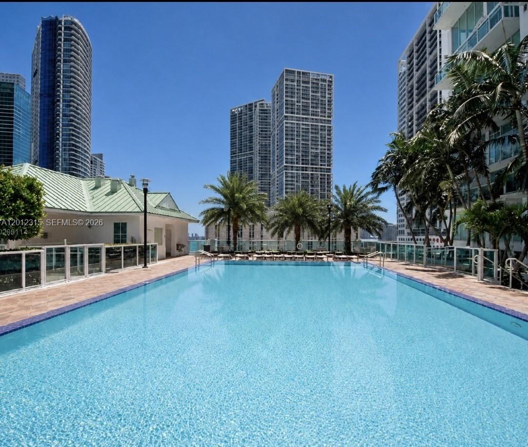 An outdoor swimming pool is surrounded by a tiled deck, palm trees, and tall buildings — 41 SE 5th St # 2011, Miami FL 33131, MIAMI, FL