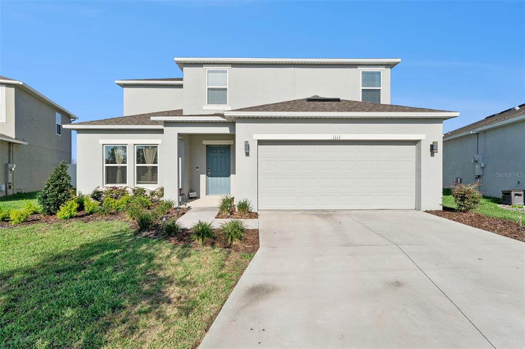 A two-story house with a light-colored stucco exterior, a two-car garage, and a front lawn — 1111 CALICO POINTE CIRCLE, GROVELAND, FL