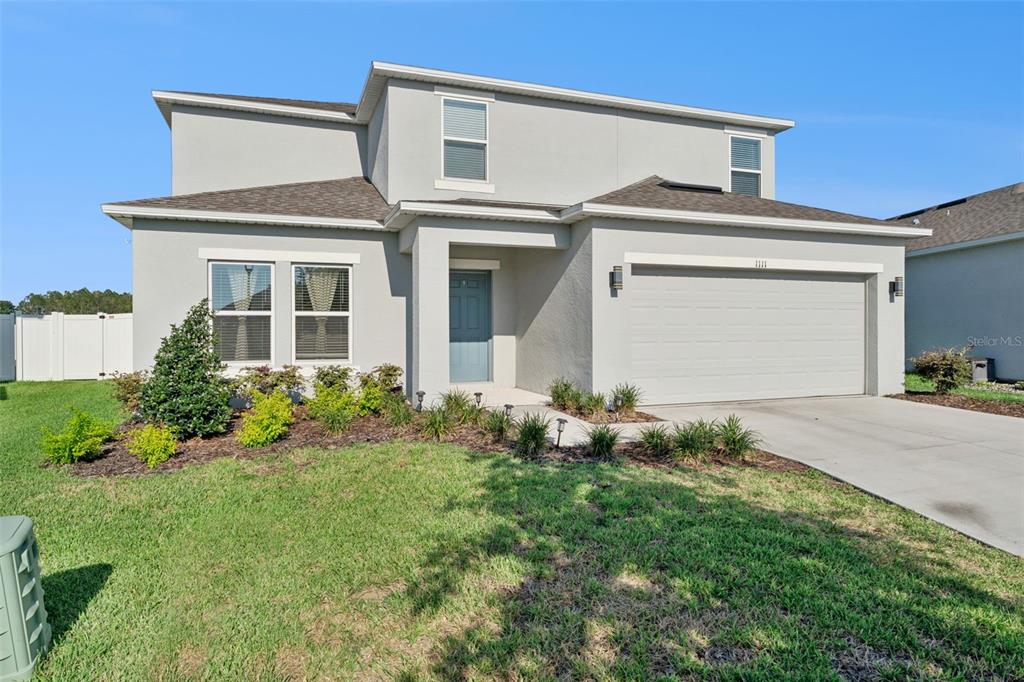 A two-story house with a light gray stucco exterior, a two-car garage, and a front lawn — 1111 CALICO POINTE CIRCLE, GROVELAND, FL