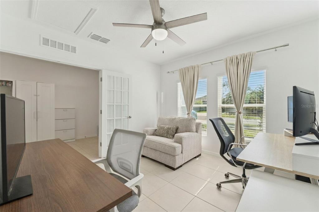 A home office features two desks, an armchair, a ceiling fan, and French doors — 1111 CALICO POINTE CIRCLE, GROVELAND, FL