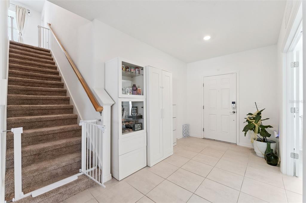 An entryway features tiled floors, a carpeted staircase with a gate, and white storage cabinets — 1111 CALICO POINTE CIRCLE, GROVELAND, FL