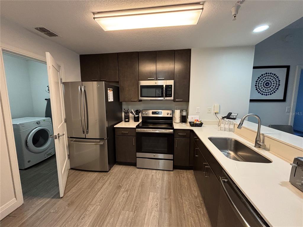 A kitchen with dark cabinets, stainless steel appliances, and light countertops features wood-look flooring — 14501 GROVE RESORT AVENUE UNIT 3304, WINTER GARDEN, FL