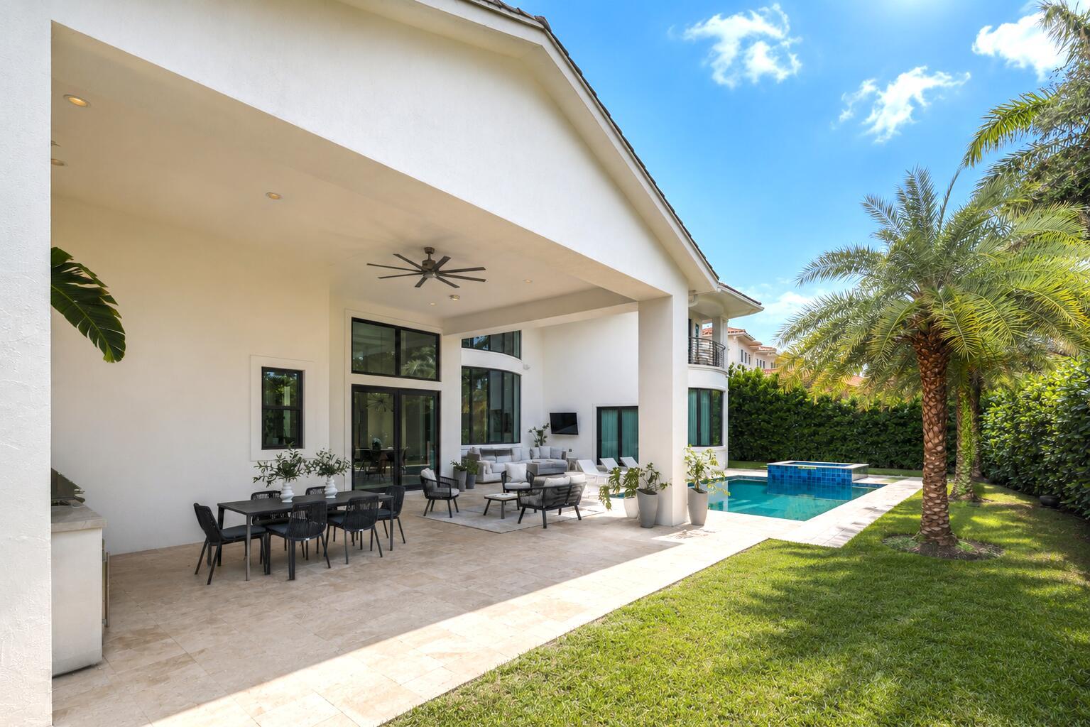 A covered patio features outdoor dining and lounge furniture overlooking a swimming pool and lawn — 2702 NW 71st Boulevard, Boca Raton FL 33496, BOCA RATON, FL