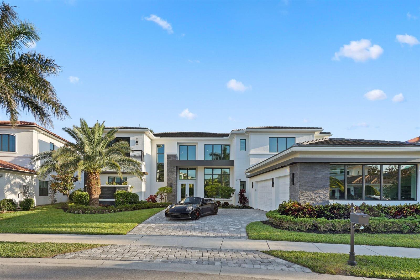 A modern two-story house with a paved driveway and a black sports car parked outside — 2702 NW 71st Boulevard, Boca Raton FL 33496, BOCA RATON, FL