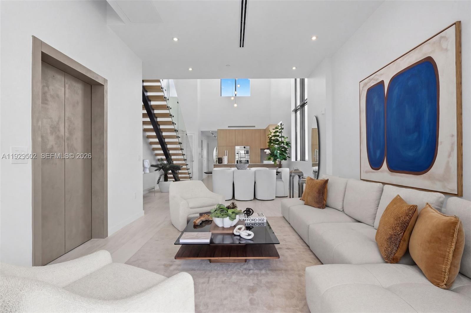 A modern living room features a large sectional sofa, glass coffee table, and open staircase — 756 84th St # C, Miami Beach FL 33141, MIAMI BEACH, FL