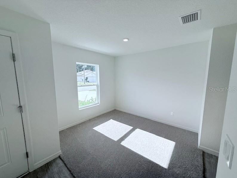 A small room with gray carpet, white walls, a single window, and a white door — 25 ROUND THORN DRIVE, PALM COAST, FL