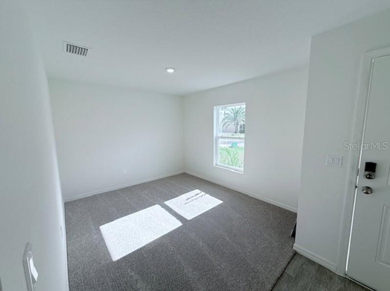 A carpeted room with white walls, a single window, and a door on the right — 25 ROUND THORN DRIVE, PALM COAST, FL