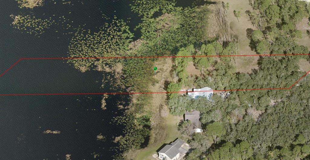 This aerial view shows a waterfront property with a house and trees outlined in red — 2332 MITCHELL ISLAND ROAD, DELTONA, FL