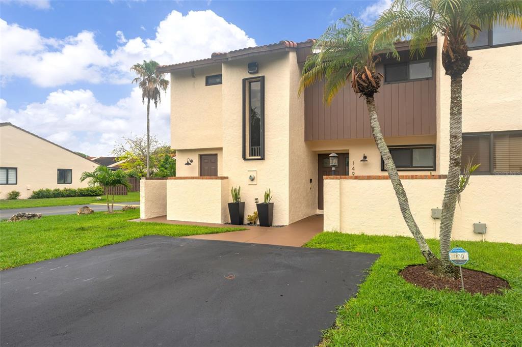 A two-story townhouse with beige stucco walls, a brown front door, and a palm tree — 14932 SW 89TH ST, MIAMI, FL