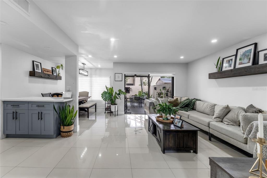 A bright, open-concept living room features white tile floors, a gray sectional, and patio access — 14932 SW 89TH ST, MIAMI, FL