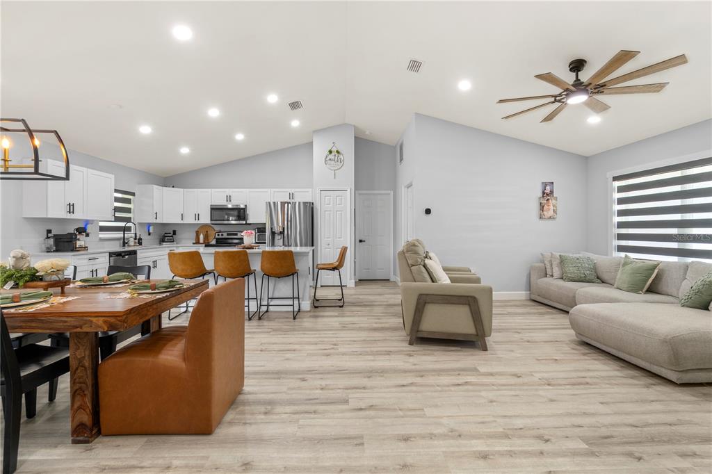 An open-concept living room and kitchen with light wood flooring and white cabinetry — 13210 SW 112TH PLACE, DUNNELLON, FL