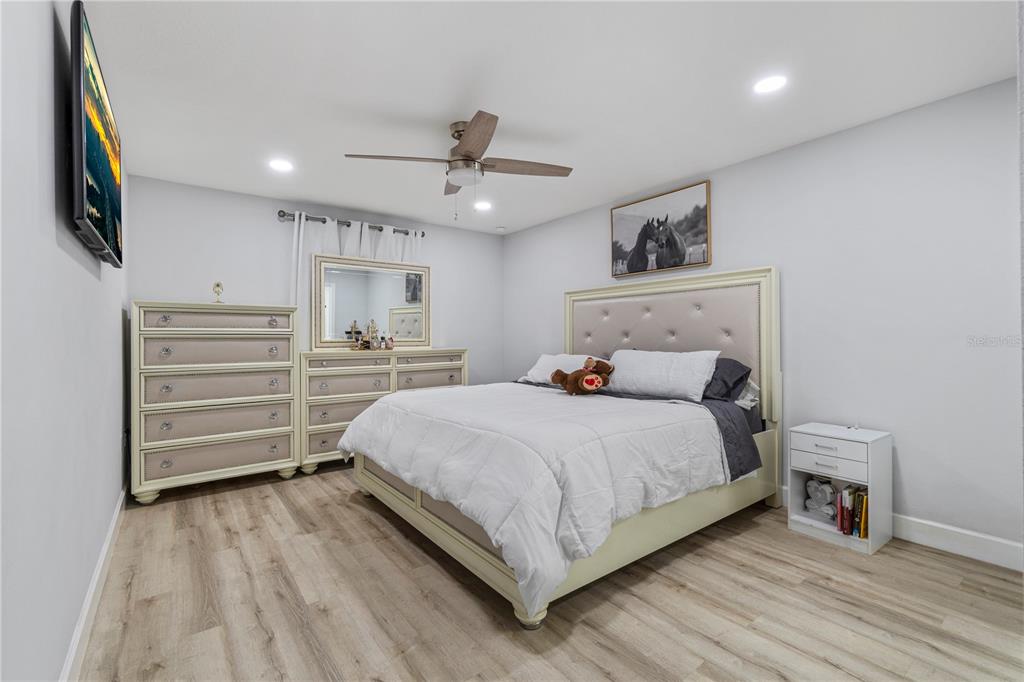 A bedroom features a light-colored bed, matching dresser and nightstand, and wood-look flooring — 13210 SW 112TH PLACE, DUNNELLON, FL
