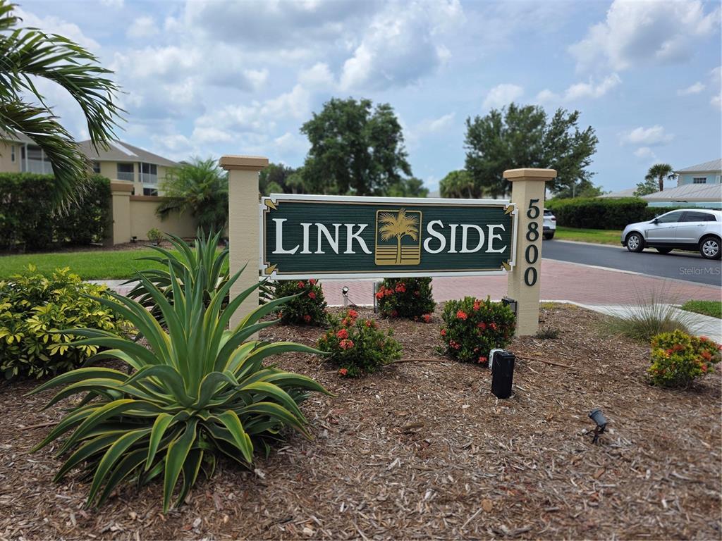 A sign for Link Side stands in a landscaped garden bed near a paved road — 5800 SABAL TRACE DRIVE UNIT 1201, NORTH PORT, FL