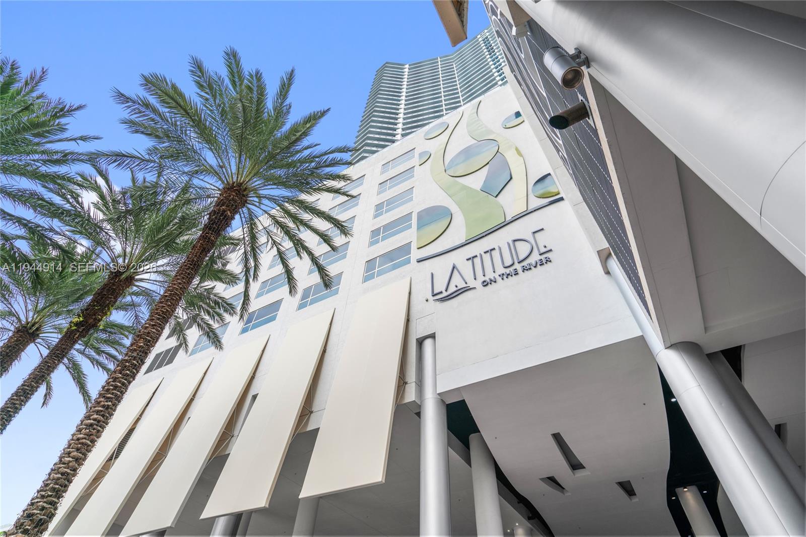 A low-angle view shows the exterior of the Latitude on the River building with palm trees — 185 SW 7th St # 2702, Miami FL 33130, MIAMI, FL