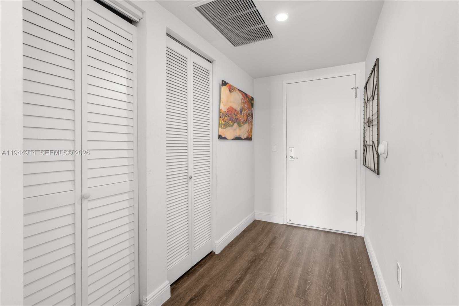 A hallway features white louvered closet doors, wood-look flooring, and a white entry door — 185 SW 7th St # 2702, Miami FL 33130, MIAMI, FL