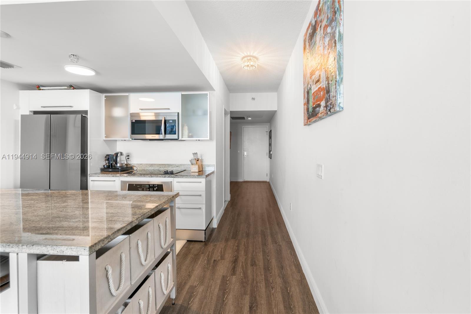 A modern kitchen features white cabinetry, stainless steel appliances, and a granite-topped island — 185 SW 7th St # 2702, Miami FL 33130, MIAMI, FL