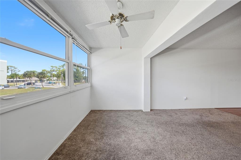 A sunroom with white walls, brown carpeting, a ceiling fan, and large windows — 2300 AARON STREET UNIT 204, PORT CHARLOTTE, FL