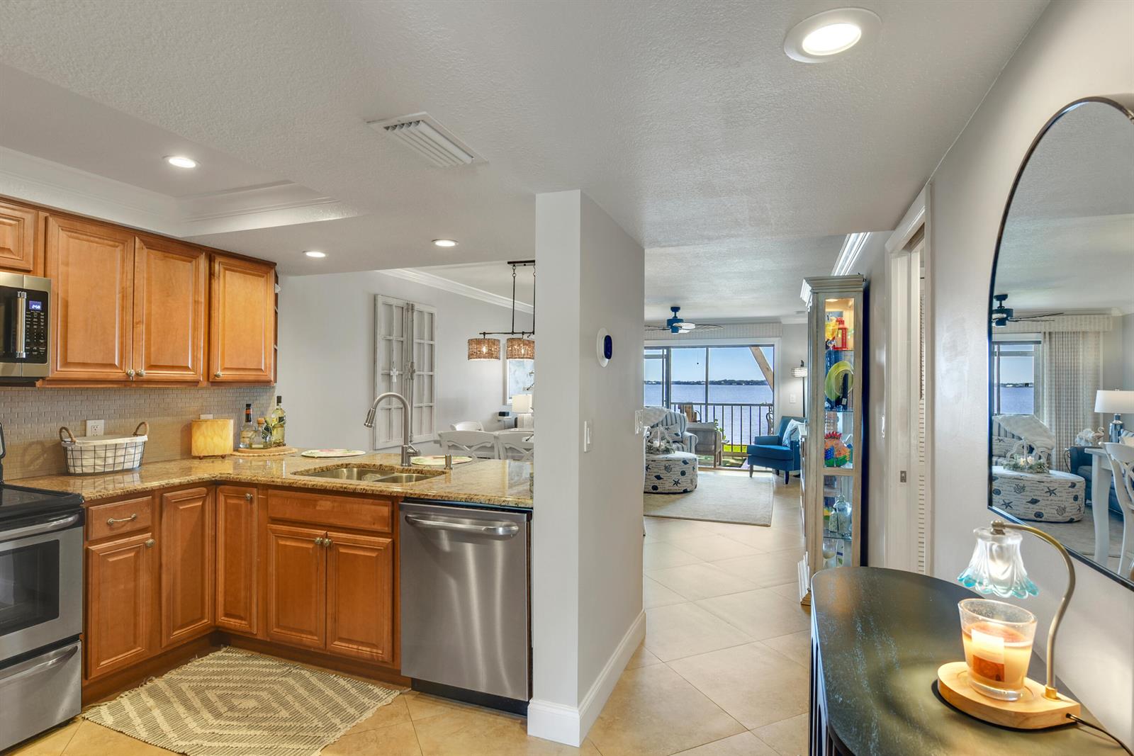 A kitchen with wood cabinets and granite countertops opens to a living area with water views — 4440 NE Sandpebble Trace # 104, Stuart FL 34996, STUART, FL