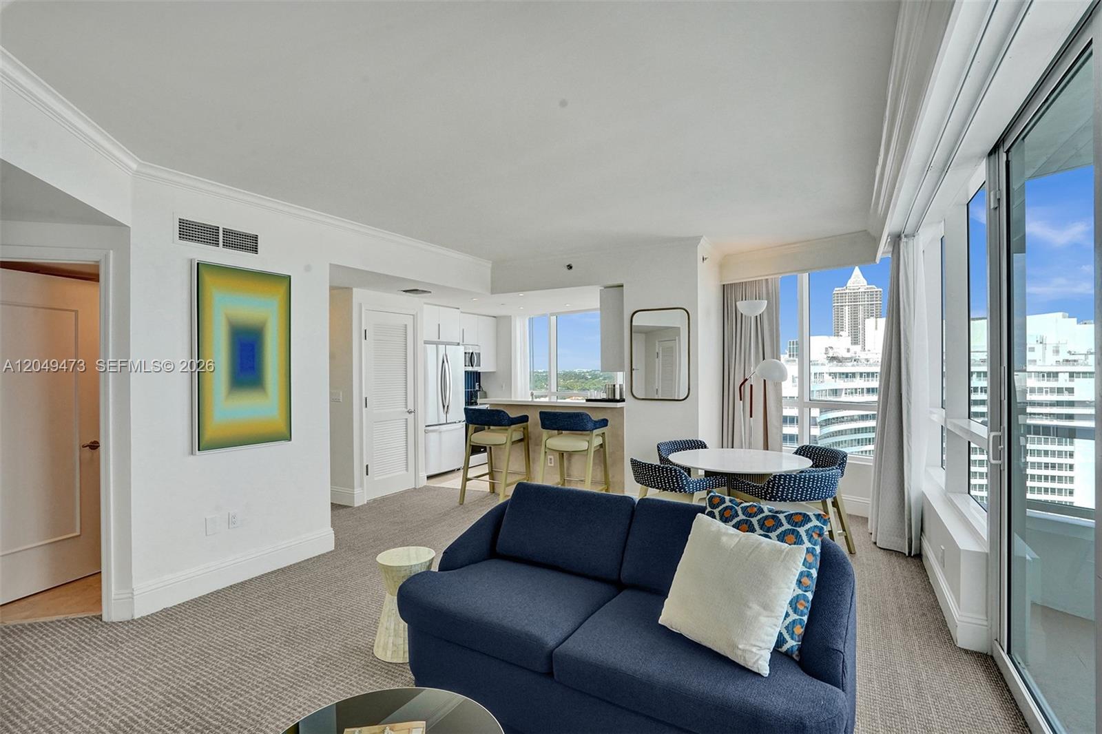 A living room with a blue sofa, dining area, kitchen counter, and city skyline views — 4401 Collins Ave # 1503, Miami Beach FL 33140, MIAMI BEACH, FL