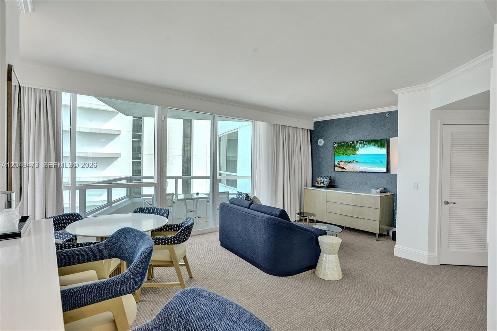A living room features a blue sofa, dining area, and a television on a wall — 4401 Collins Ave # 1503, Miami Beach FL 33140, MIAMI BEACH, FL