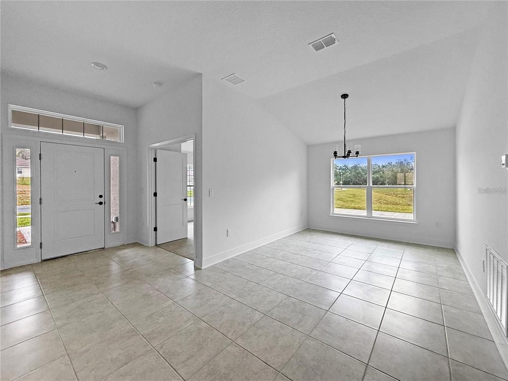 An entryway leads into a dining area with tile flooring, a vaulted ceiling, and windows — 1654 ANN ROSE WAY, LEESBURG, FL