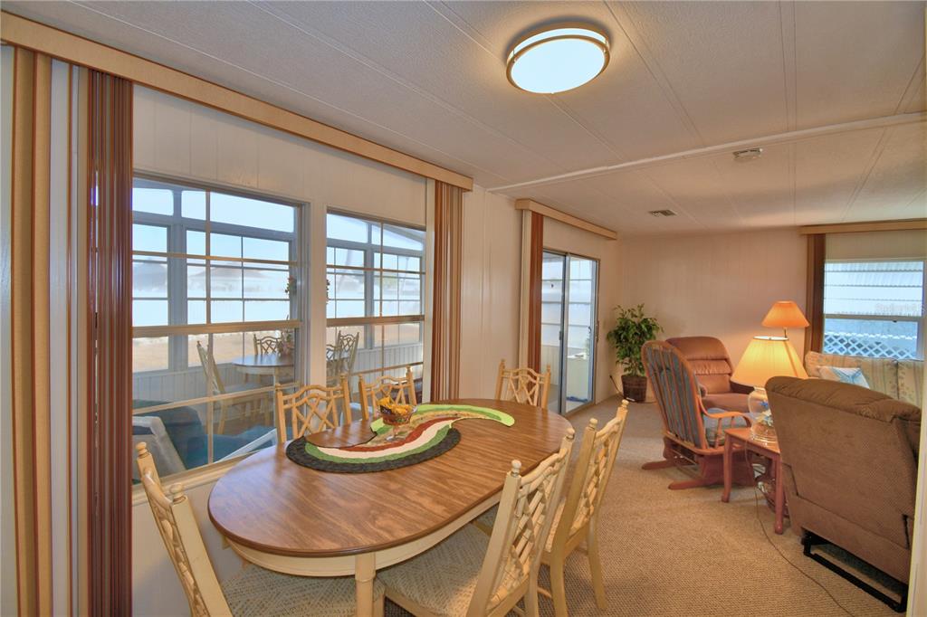 A dining area with a wooden table and chairs adjacent to a carpeted living room — 4228 CEDARWOOD STREET, WINTER HAVEN, FL