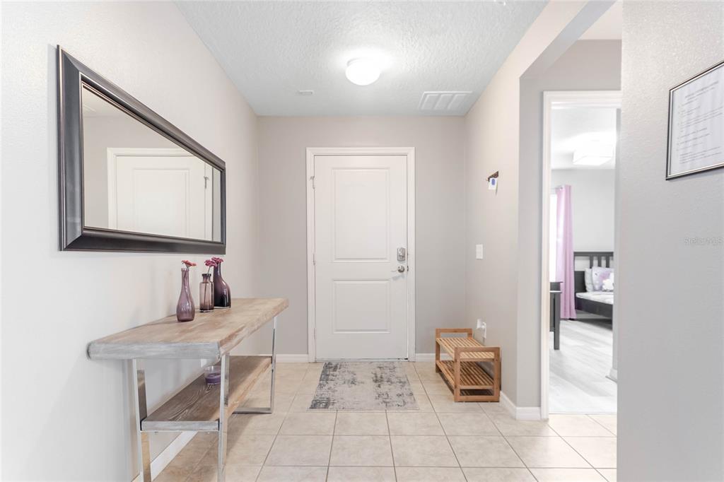 An entryway features a console table, a wall mirror, tile flooring, and a white door — 4740 BLUE DIAMOND STREET, KISSIMMEE, FL