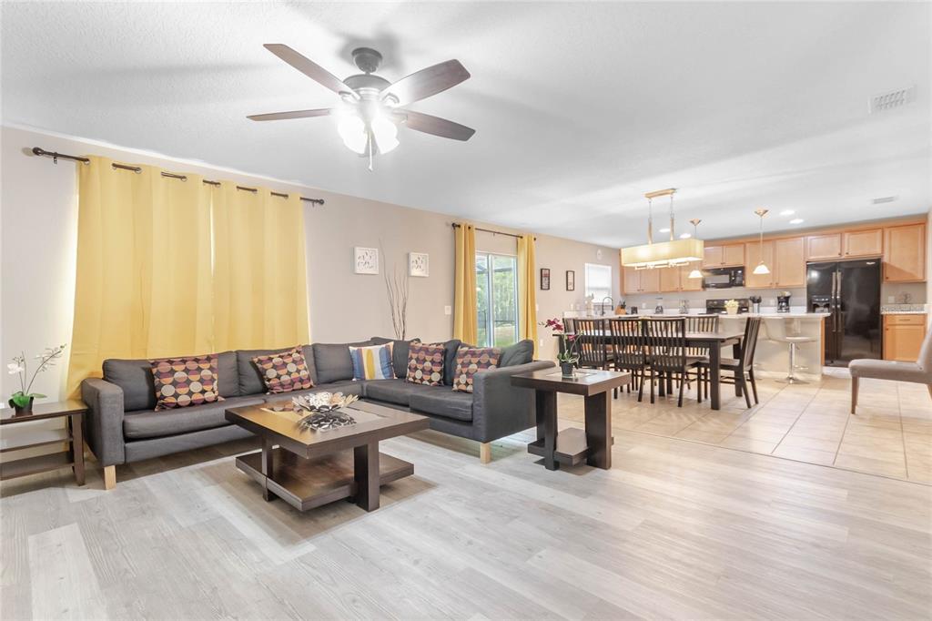 An open-concept living room and kitchen featuring gray flooring, a sectional sofa, and dining area — 4740 BLUE DIAMOND STREET, KISSIMMEE, FL