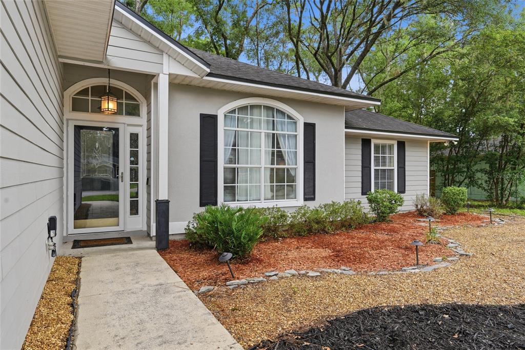 A gray house exterior features a front door with a transom window and arched windows — 5840 SW 85TH STREET, GAINESVILLE, FL