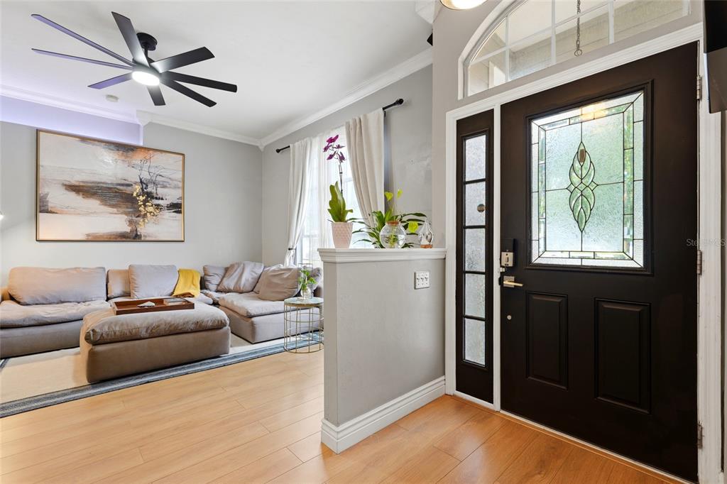 A living room with light wood floors, a sectional sofa, and a dark front door — 5840 SW 85TH STREET, GAINESVILLE, FL