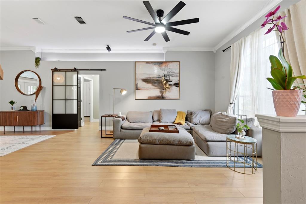 A living room features a grey sectional sofa, a ceiling fan, and a sliding barn door — 5840 SW 85TH STREET, GAINESVILLE, FL