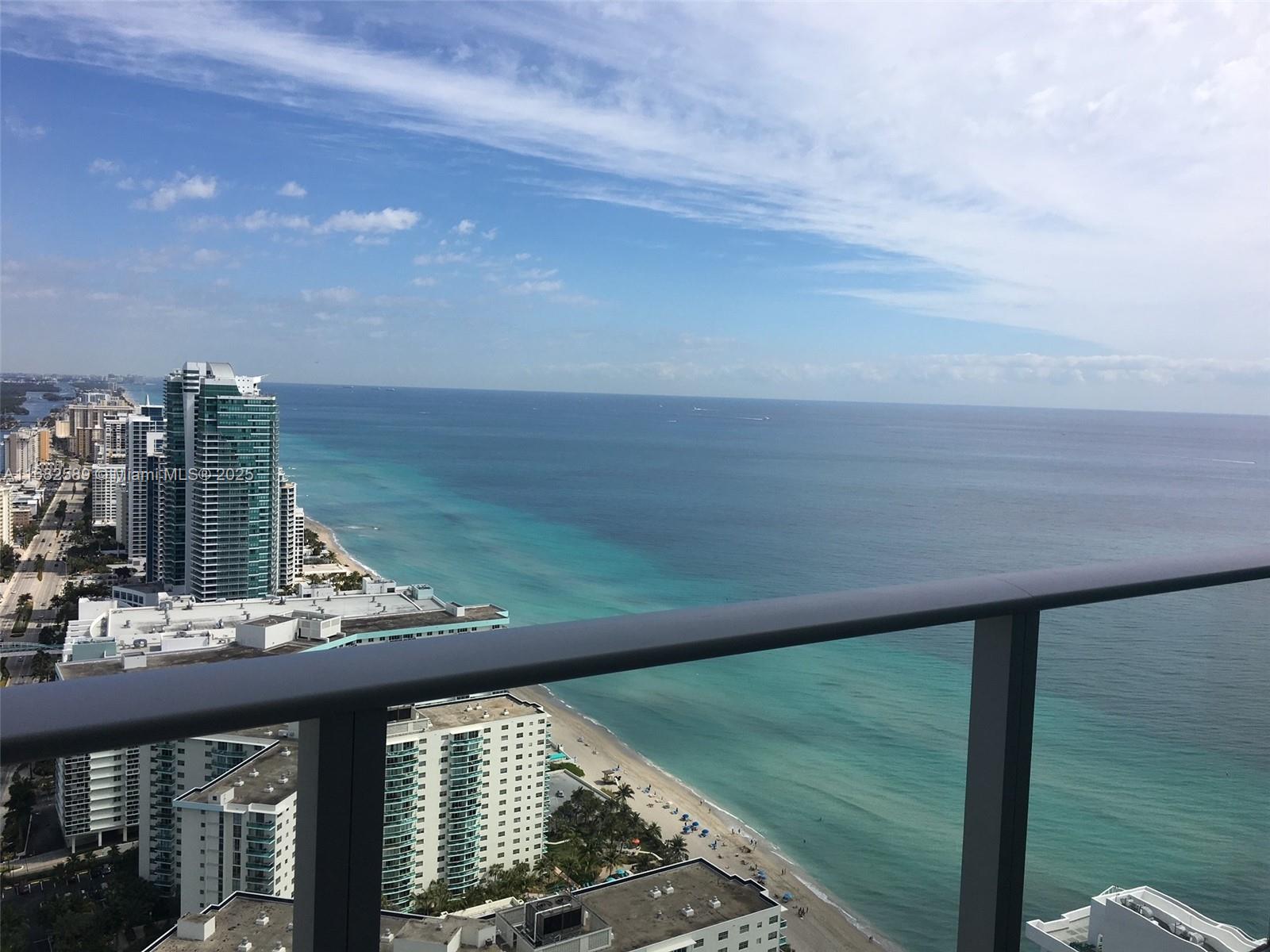 A high-angle view from a balcony overlooking a beach, ocean, and coastal high-rise buildings — 4111 S Ocean Dr # 3312, Hollywood FL 33019, HOLLYWOOD, FL