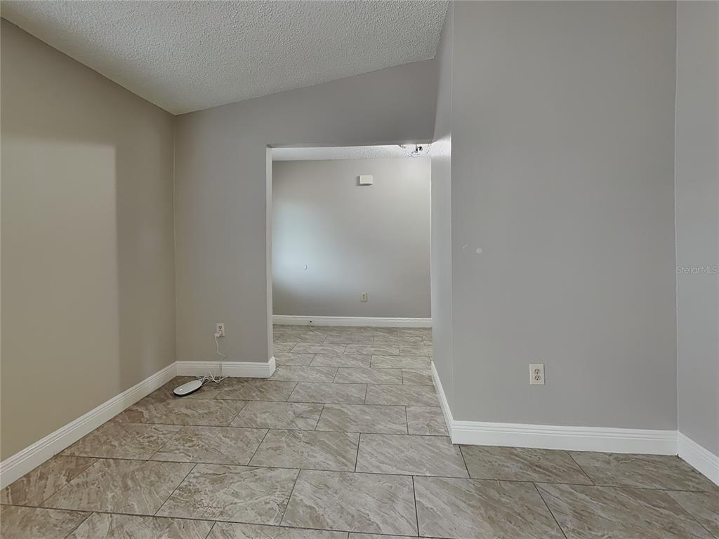 A room with gray walls and tiled flooring leads into an adjacent space — 488 NORTHVIEW STREET, PORT CHARLOTTE, FL