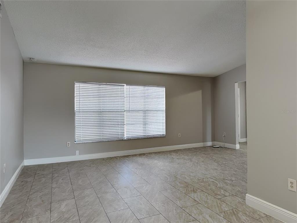 An empty room with light gray walls, tile flooring, and a large window with blinds — 488 NORTHVIEW STREET, PORT CHARLOTTE, FL