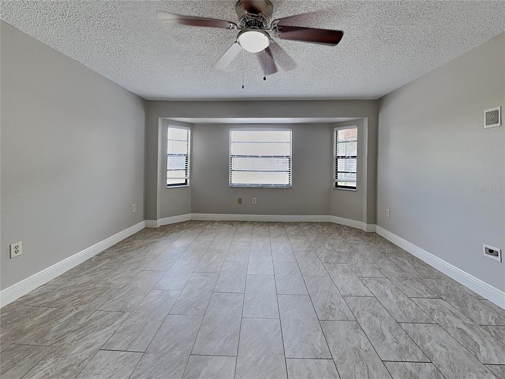 An empty room features gray walls, tile flooring, a ceiling fan, and a bay window — 488 NORTHVIEW STREET, PORT CHARLOTTE, FL