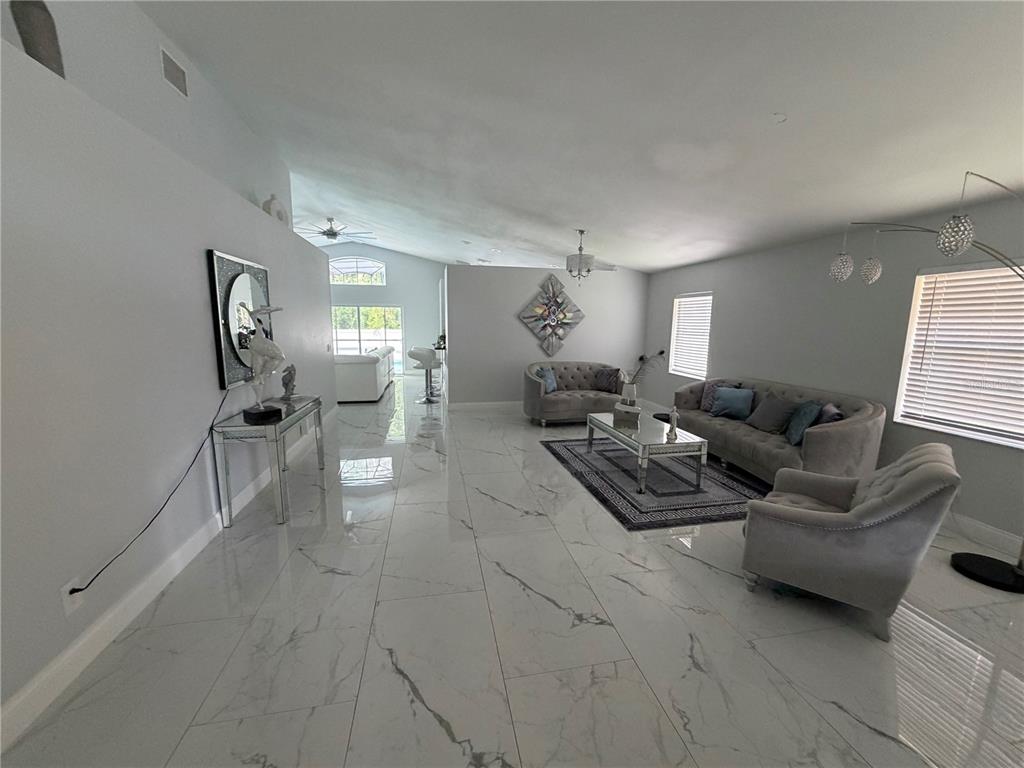 A spacious living room features large white marble-look floor tiles and gray upholstered furniture — 3264 FAIRFIELD DRIVE, KISSIMMEE, FL