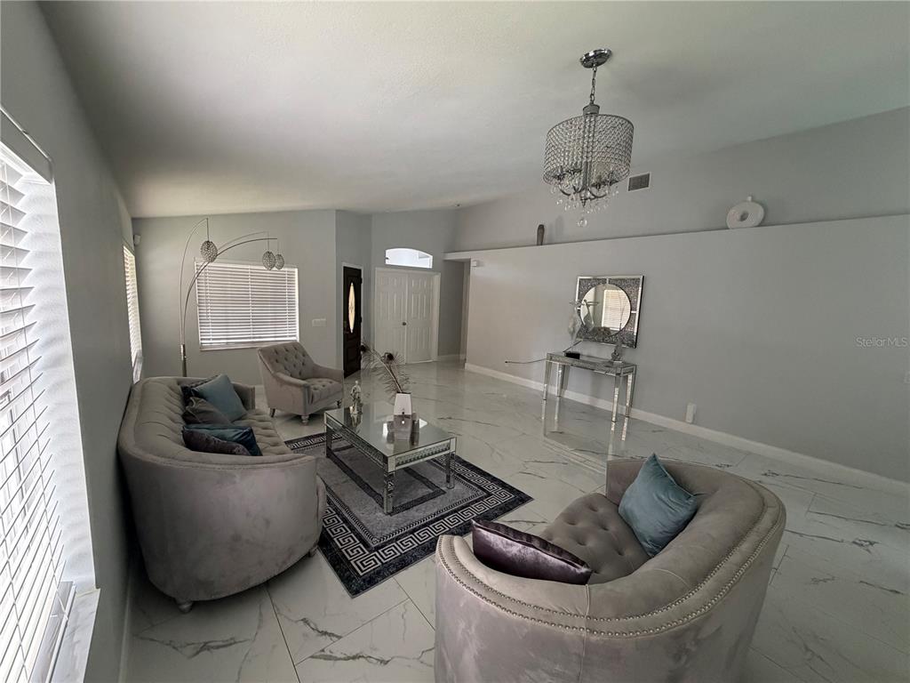 A living room features gray tufted furniture, a glass coffee table, and white marble flooring — 3264 FAIRFIELD DRIVE, KISSIMMEE, FL