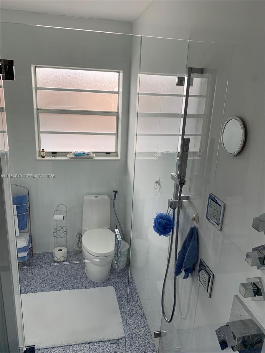A bathroom features a glass-enclosed shower, a white toilet, and a window with frosted panes — 12945 Cherry Rd, North Miami FL 33181, NORTH MIAMI, FL
