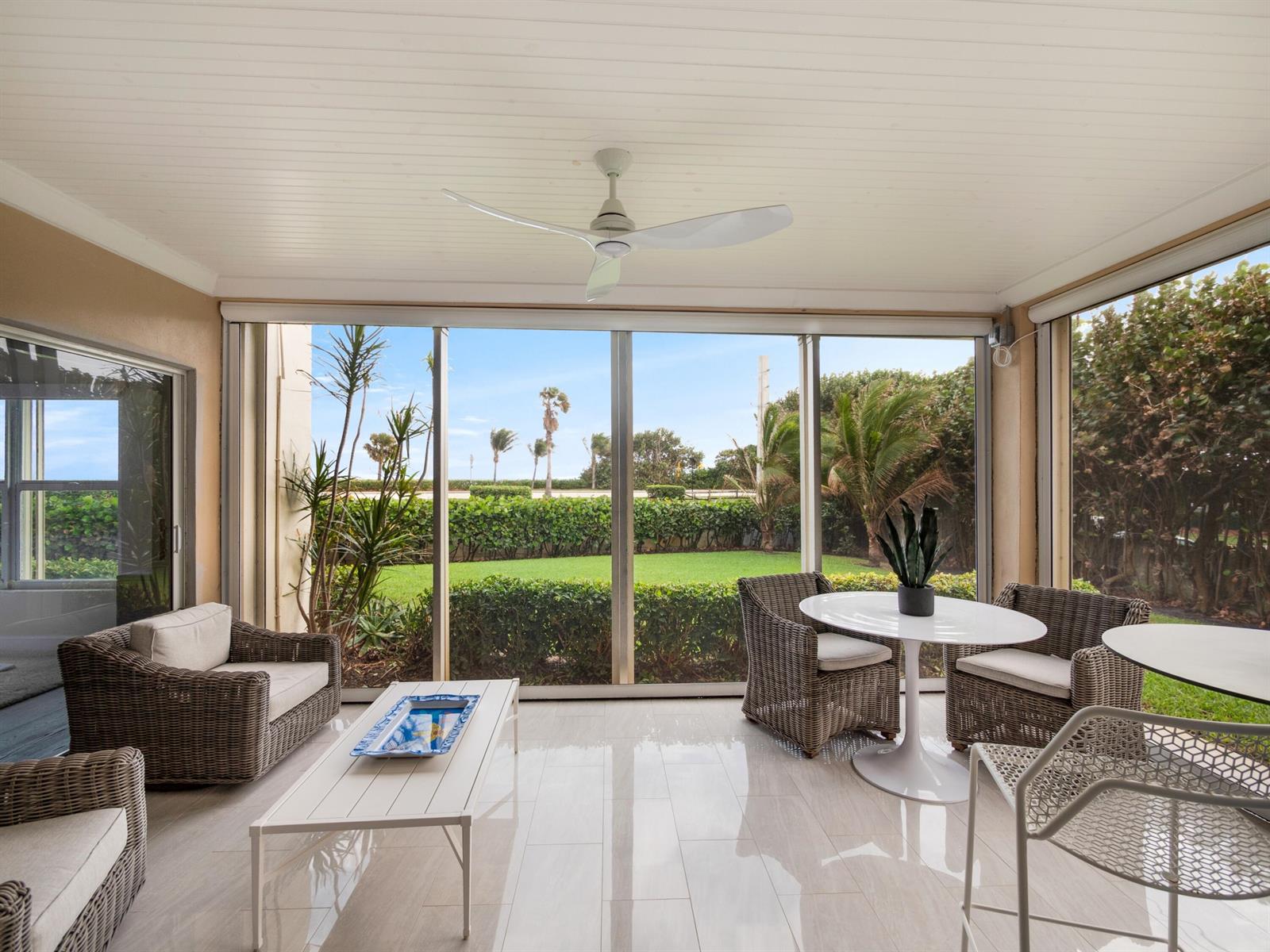 A sunroom with wicker furniture, a white coffee table, and a view of a grassy yard — 4161 S Us Highway 1 # N1, Jupiter FL 33477, JUPITER, FL