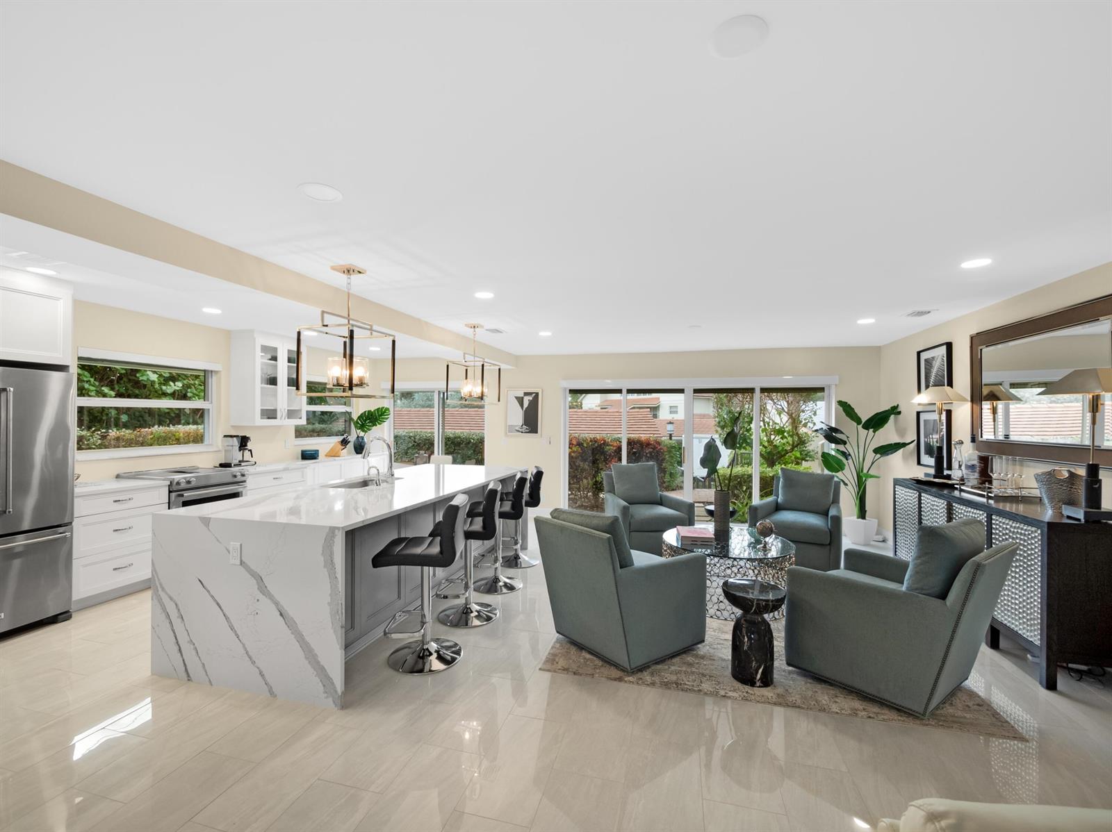An open-concept kitchen and living area features a marble island, bar stools, and four armchairs — 4161 S Us Highway 1 # N1, Jupiter FL 33477, JUPITER, FL