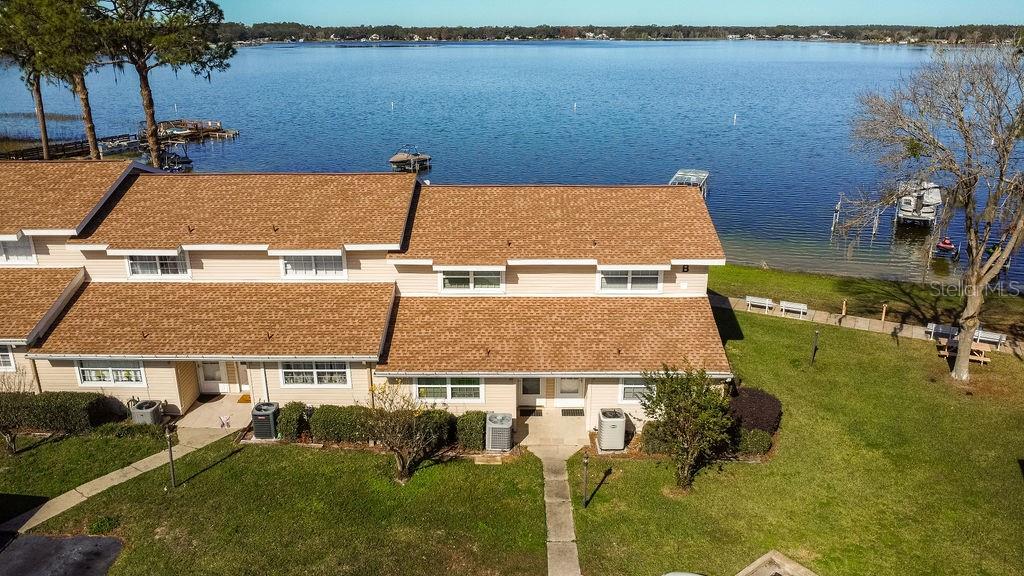 An aerial view of a multi-unit townhouse building situated along a lakefront — 11001 SE SUNSET HARBOR ROAD UNIT B10, SUMMERFIELD, FL