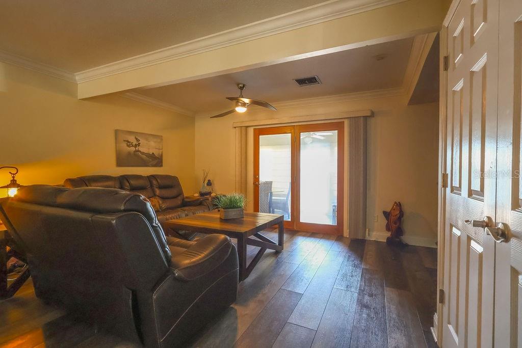 A living room features dark wood flooring, a leather sofa, a coffee table, and sliding doors — 11001 SE SUNSET HARBOR ROAD UNIT B10, SUMMERFIELD, FL